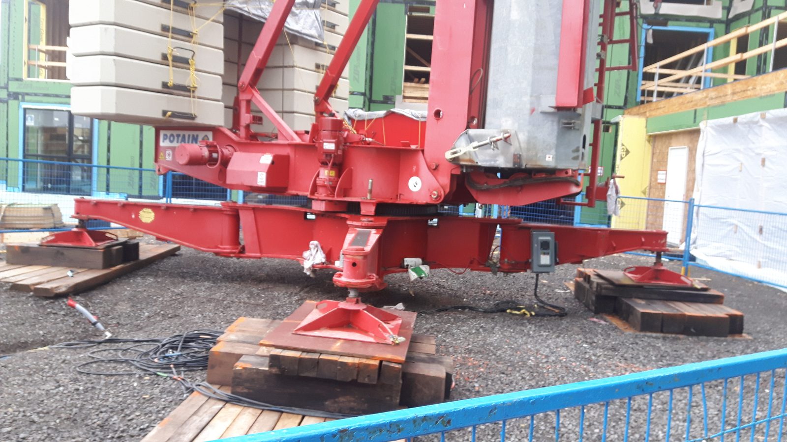 Potain self-erecting crane base set on timber cribbing at a construction site